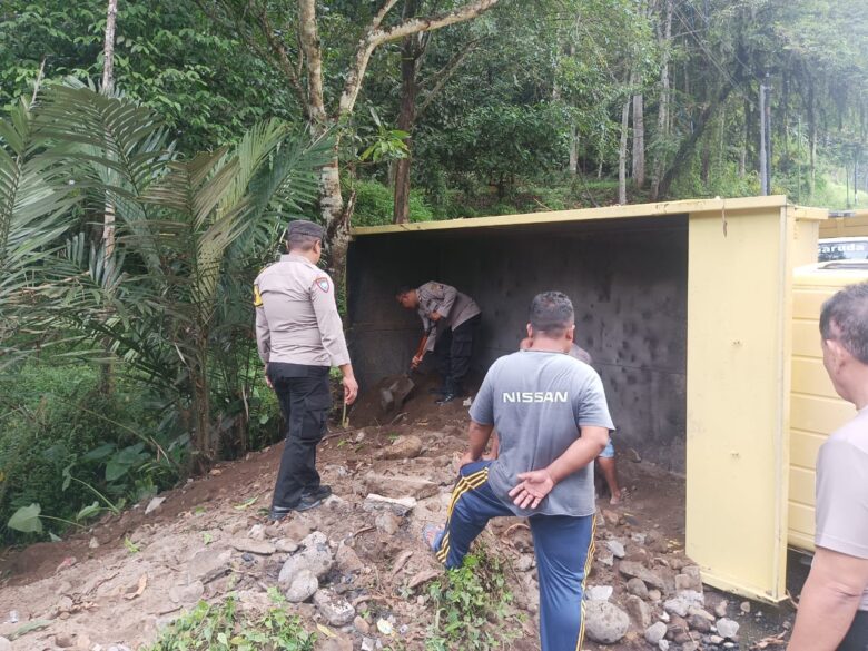 Anggota Polsek Licin membantu bersihkan tanah dan mengatur lalulintas pada insiden truk terguling di Jalan tanjakan Kecamatan Licin, Selasa (2/7/2024).(blok-a.com/Kuryanto)