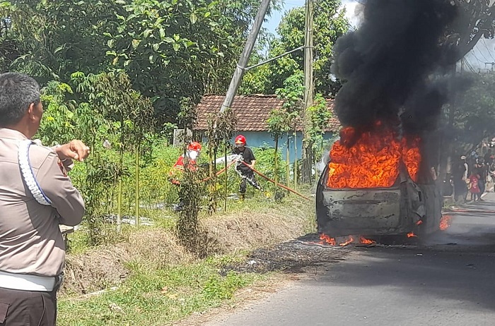Unit Damkar saat memadamkan mobil terbakar yang terjadi di Jalan Raya Jajag-Bangorejo, Kecamatan Gambiran, Senin (12/8/2024).(blok-a.com/Kuryanto)