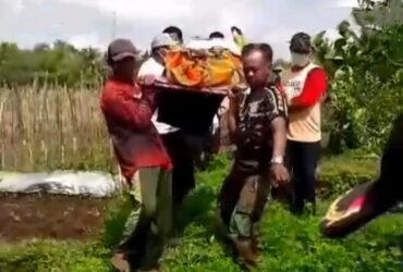 Caption : Polisi dibantu warga saat mengevakuasi mayat pria yang ditemukan meninggal di sebuah parit di area persawahan di Kecamatan Genteng, Minggu (1/8/2024)(blok-a.com/Kuryanto).