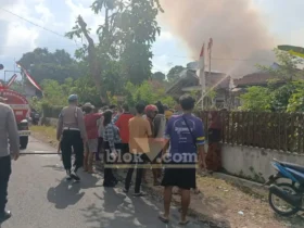 Petugas Damkar bersama polisi serta dibantu warga saat berusaha melakukan pemadaman rumah milik Sutekno, yang terbakar diduga akibat bakar sampah sembarangan, Selasa (11/08/2026) (foto: Blok-a.com/Kuryanto)